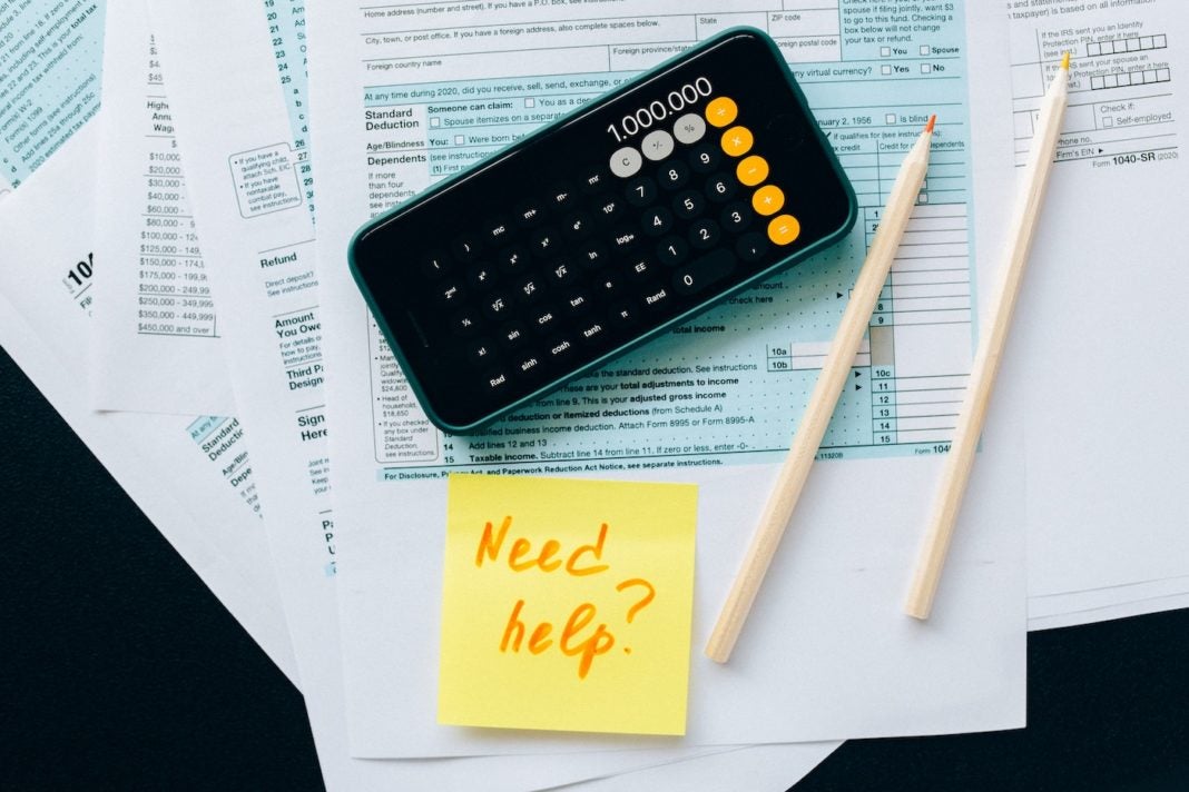 Image of calculator with tax documents and a sticky note that says 