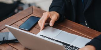 Image of business person using a laptop and mobile phone. Meant to represent Square's fintech tools.