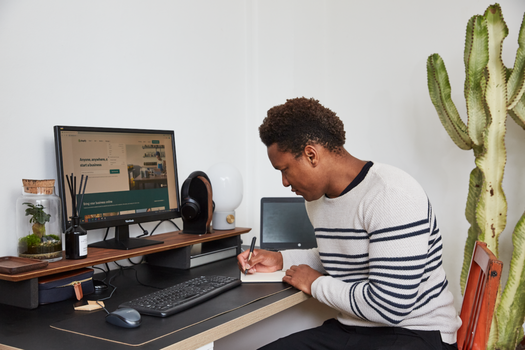 Image of business person working at a computer with Shopify pulled up in desktop browser window.