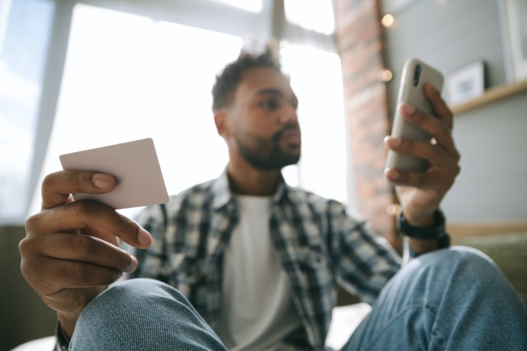 Image of business person holding a credit card in one hand and a credit card in the other.