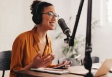 woman podcaster sitting at desk speaking into microphone