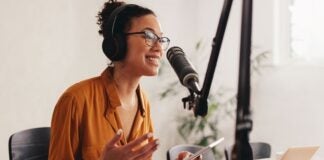 woman podcaster sitting at desk speaking into microphone